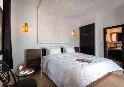 a bedroom with a large white bed and a table at Riad Tamazgha in Marrakech