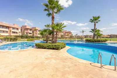 a swimming pool with palm trees in a resort at Luxury Living Flat in Prestigia Marrakech in Marrakech