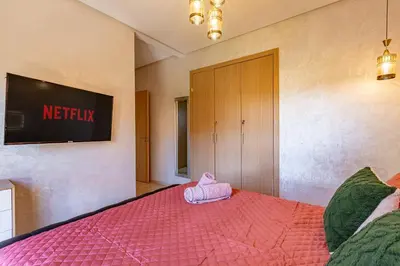 a bedroom with a pink bed with a tv on the wall at Luxury Living Flat in Prestigia Marrakech in Marrakech