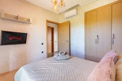 a bedroom with a bed and a tv on the wall at Luxury Living Flat in Prestigia Marrakech in Marrakech