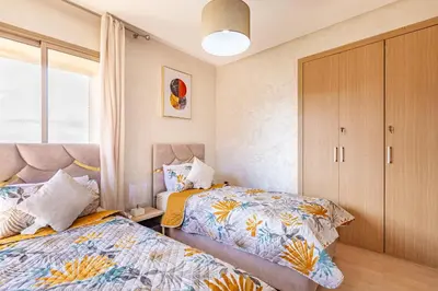 a bedroom with two beds and a large window at Luxury Living Flat in Prestigia Marrakech in Marrakech