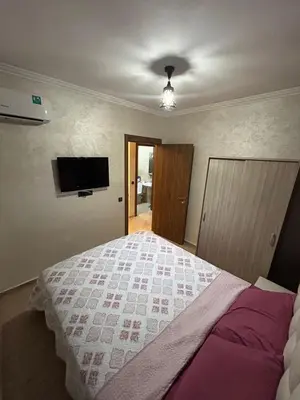a bedroom with a bed and a flat screen tv at Studio au centre ville de marrakech avec piscine in Marrakech