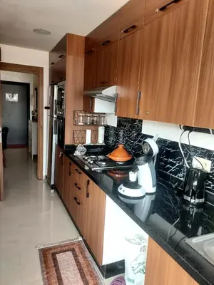 a kitchen with black counter tops and wooden cabinets at Calista Appart hotel piscine in Marrakech