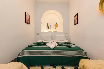a bedroom with a bed with a green blanket at Riad Mama in Marrakech