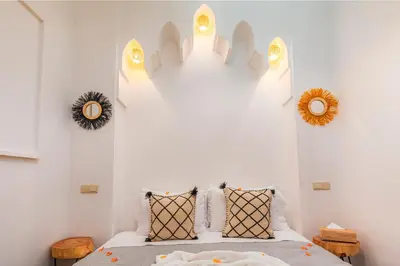 a bedroom with a bed and two mirrors on the wall at Riad Mama in Marrakech