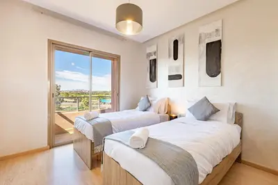 two beds in a room with a balcony at Perle Rare A Prestigia 2 Ch Avec Vue Incroyable in Marrakech