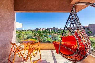 a hanging hammock on a balcony with a table and chairs at Perle Rare A Prestigia 2 Ch Avec Vue Incroyable in Marrakech