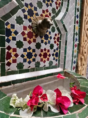 a table with flowers and a tiled wall at Riad yazuinaa in Marrakech