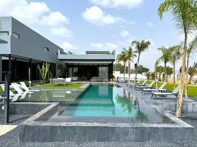 a swimming pool in front of a building with chairs at Palais Kahli in Marrakech