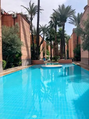 a large blue swimming pool with palm trees in the background at Riad Lalla Aicha -Piscine, 3 suites climatisées & terrasse in Marrakech