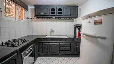 a kitchen with black cabinets and a white refrigerator at Riad Lalla Aicha -Piscine, 3 suites climatisées & terrasse in Marrakech