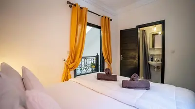 a bedroom with a large white bed and a window at Riad Lalla Aicha -Piscine, 3 suites climatisées & terrasse in Marrakech