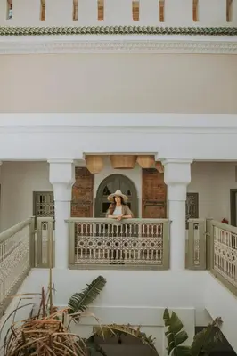a woman in a hat sitting on a balcony at Riad Dar M in Marrakech