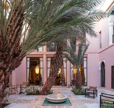 a courtyard with palm trees in front of a pink building at Riad Dar Al Dall - This Time Tomorrow in Marrakech in Marrakech