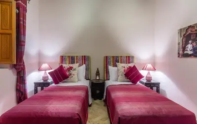 two beds in a room with two lamps at Riad Des Nations in Marrakech