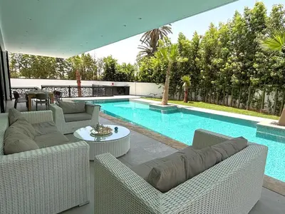 a swimming pool with wicker furniture next to a swimming pool at Palais Thami in Marrakech