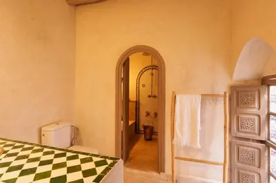 a hallway leading to a bathroom with a checkerboard patterned floor at Riad Kiwi - Private Historic Riad Jacuzzi & Hammam - Entire Home in Marrakech