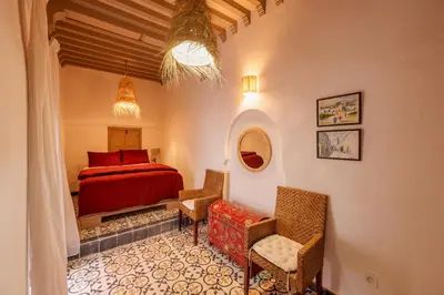 a bedroom with a bed and chairs in a room at Riad Kiwi - Private Historic Riad Jacuzzi & Hammam - Entire Home in Marrakech