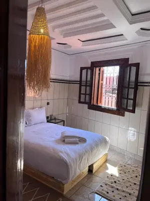 a bedroom with a bed and a window and a chandelier at Riad Dar Zarbia in Marrakech
