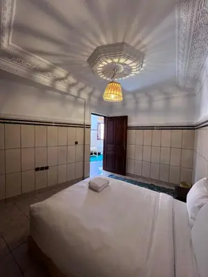 a bedroom with a large white bed and a chandelier at Riad Dar Zarbia in Marrakech