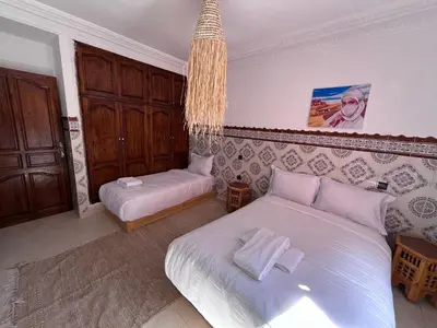 a bedroom with two beds and a chandelier at Riad Dar Zarbia in Marrakech