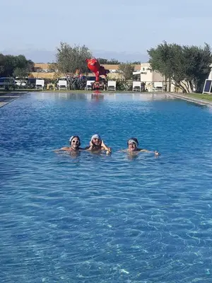 three people are swimming in a swimming pool at THE FARM LODGES & Private pool in Marrakech