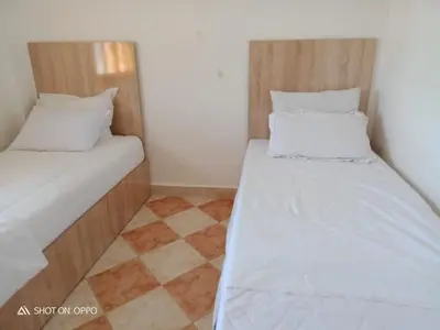 two beds in a small room with a checkered floor at Airport Home in Marrakech