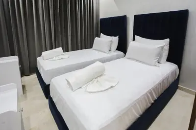 two beds in a hotel room with white sheets at Golden Skyline – Marrakech in Marrakech