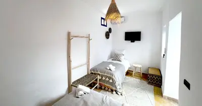 a white room with a bed and a tv at Couloirs de la Médina in Marrakech
