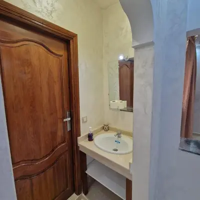 a bathroom with a sink and a wooden door at Bel appartement de 2 chambres L in Marrakech