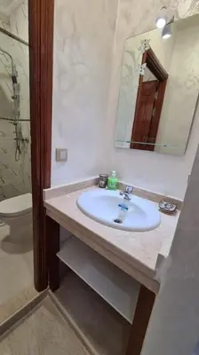a bathroom with a sink and a mirror and a toilet at Bel appartement de 2 chambres L in Marrakech