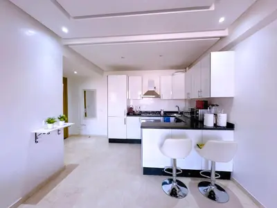 a kitchen with white cabinets and two bar stools at Cosy Hyper centre Bd Hassan 2 in Marrakech