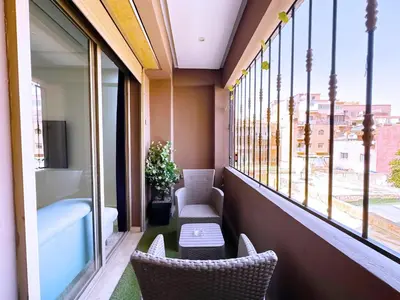 a balcony with two chairs and a table and windows at Cosy Hyper centre Bd Hassan 2 in Marrakech