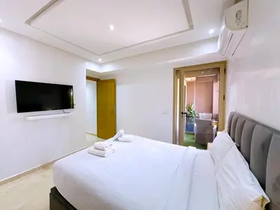 a white bedroom with a bed and a flat screen tv at Cosy Hyper centre Bd Hassan 2 in Marrakech