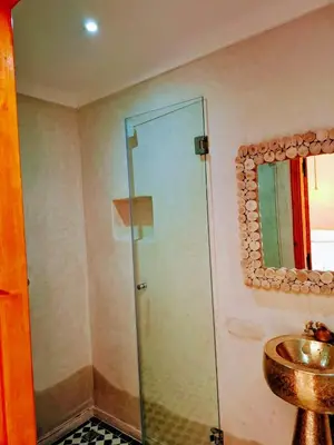 a bathroom with a glass shower and a sink at Duplex Riad Abjaou in Marrakech