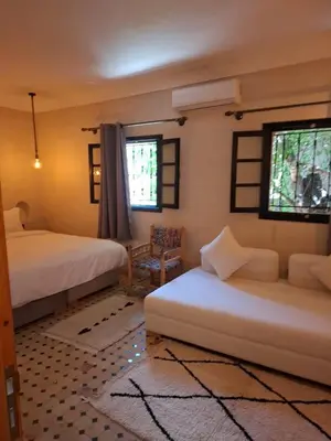 a bedroom with two beds and two windows at Duplex Riad Abjaou in Marrakech