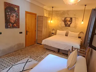 a bedroom with a bed and a chair in it at Duplex Riad Abjaou in Marrakech