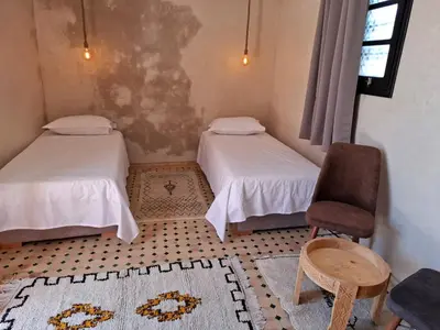a small room with two beds and a chair at Duplex Riad Abjaou in Marrakech