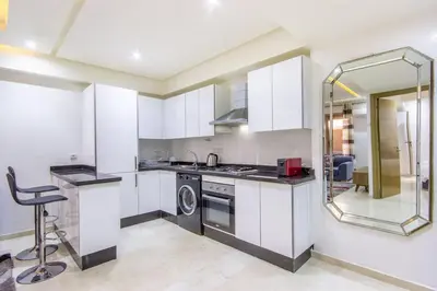 a kitchen with white cabinets and a sink and a dishwasher at NEW! Plein Gueliz, wifi, terrasse in Marrakech