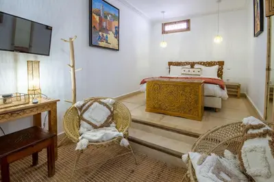 a bedroom with a bed and a television and chairs at Riad Bab Aljana in Marrakech