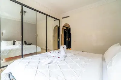 a bedroom with a large white bed and a mirror at Appartement Haut standing Gueliz Plaza in Marrakech
