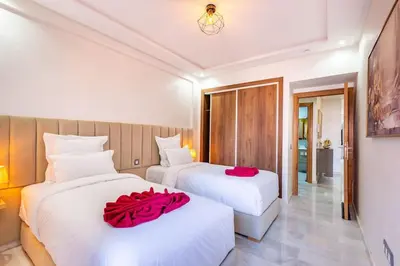 two beds in a hotel room with red pillows on them at Charmante Wohnung im Herzen von Marrakesch Gueliz in Marrakech