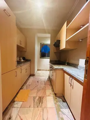 a kitchen with wooden cabinets and a tile floor at Appartement Spacieux avec Piscine à la Palmeraie in Marrakech