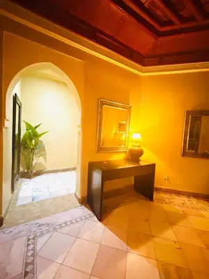 a living room with a table and a yellow wall at Appartement Spacieux avec Piscine à la Palmeraie in Marrakech