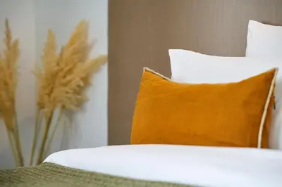 a bed with a pillow and a vase with flowers at Riad Dar Nakous in Marrakech
