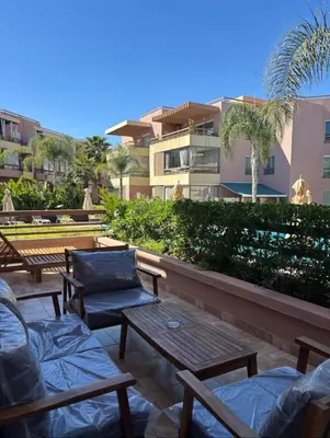 a patio with tables and chairs and a building at Riad Gardens Two Bedroom Apartment in Marrakech
