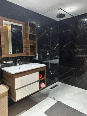 a bathroom with a shower with a sink and a glass shower door at Appartement Luxueux au Rooftop à Guéliz in Marrakech