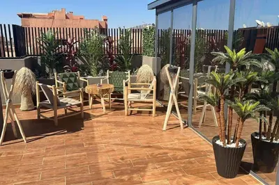 a patio with chairs and tables on a roof at Appartement Luxueux au Rooftop à Guéliz in Marrakech