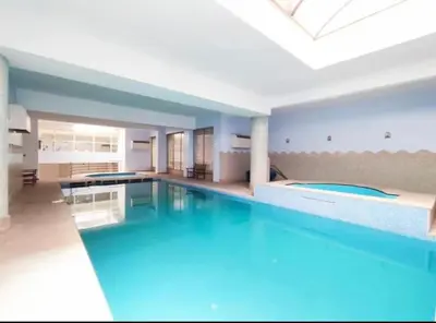 a large swimming pool with blue water in a building at Joli appartement Gueliz centre ville in Marrakech