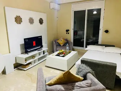 a living room with a bed and a tv at Joli appartement Gueliz centre ville in Marrakech